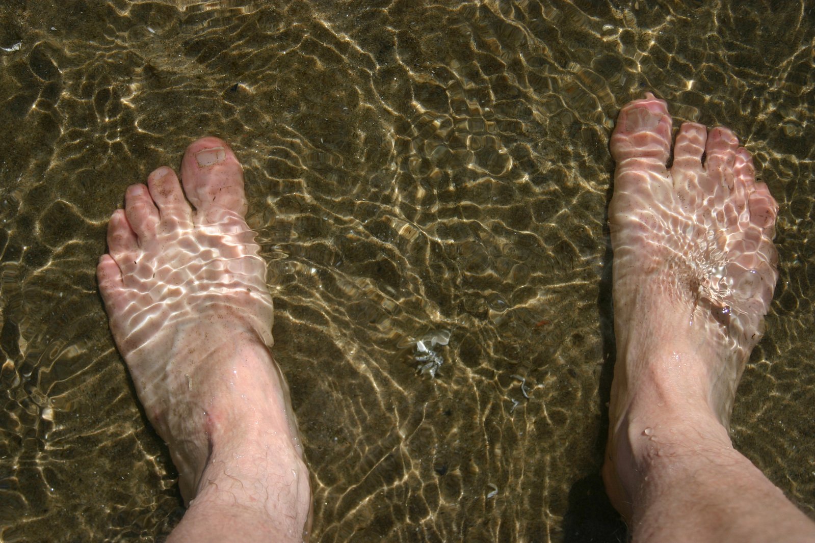 a person standing in water with his bare feet up