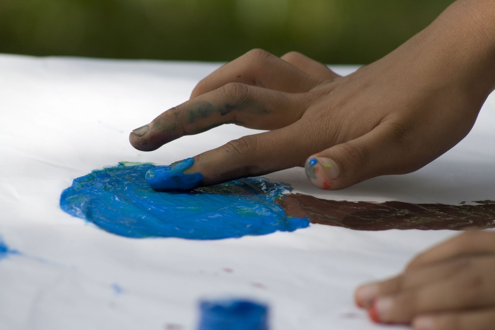 two hands on a table painting blue on it