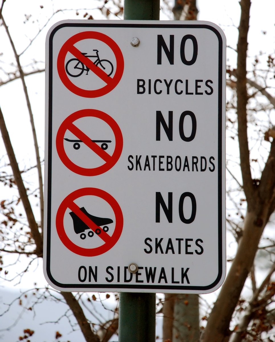 the no skateboarding, bike and no skateboard sign is posted on a post