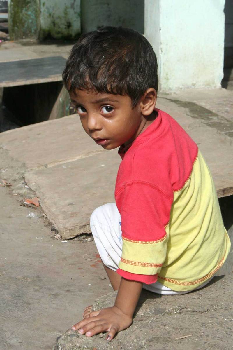 a boy in red shirt sitting on concrete next to cement block