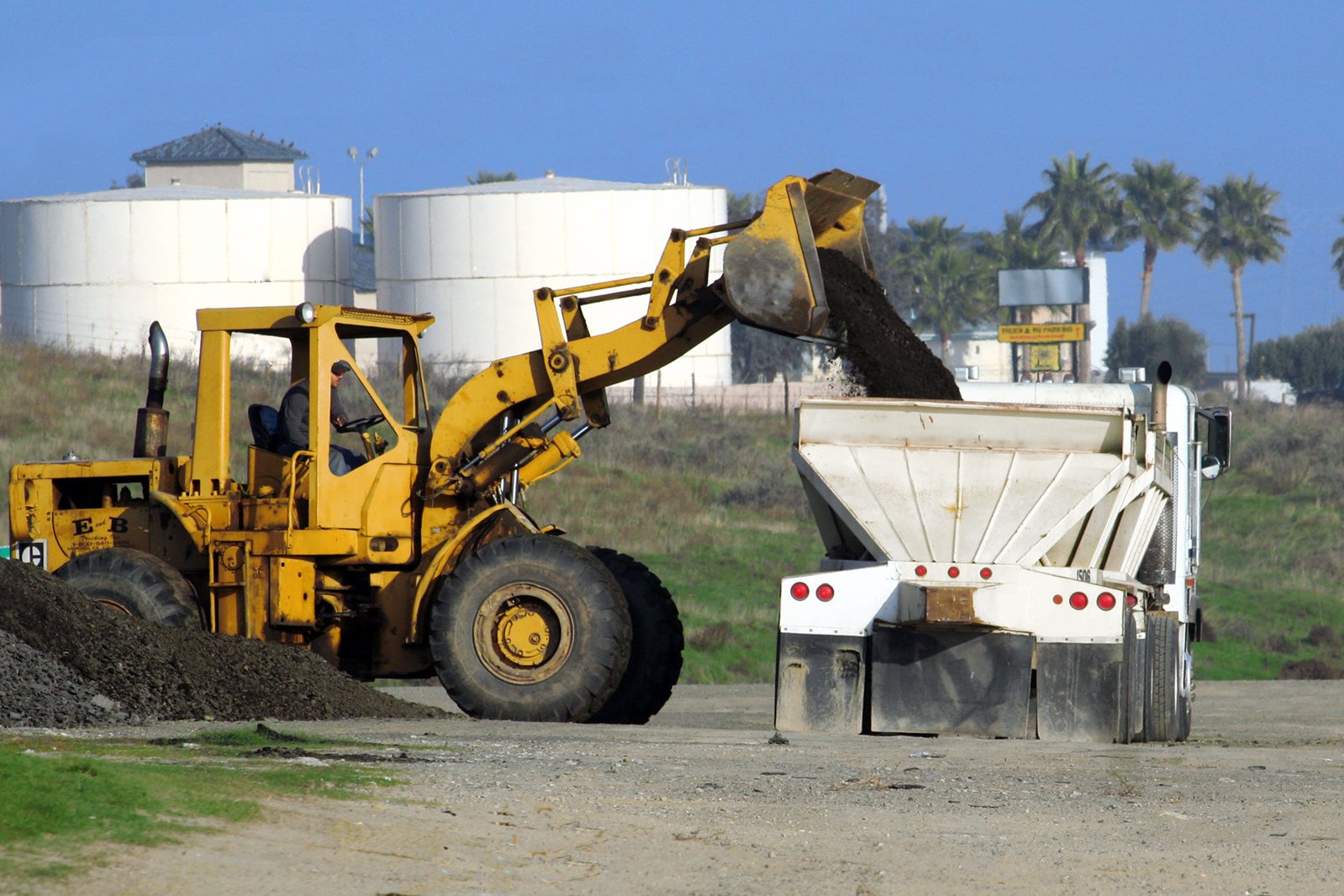 a big tractor is dumping dirt in a dump area