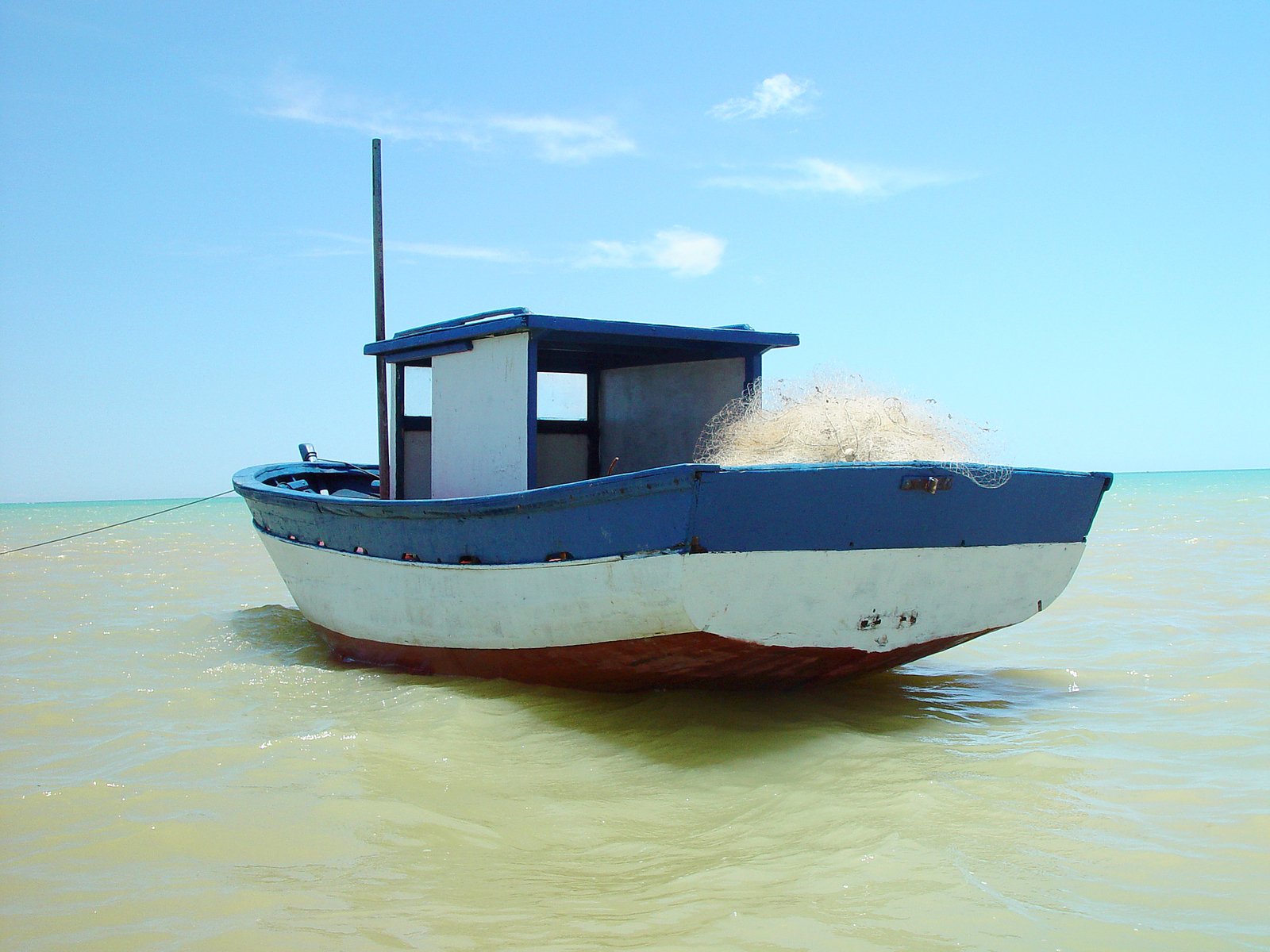 the small fishing boat is coming down the ocean shore