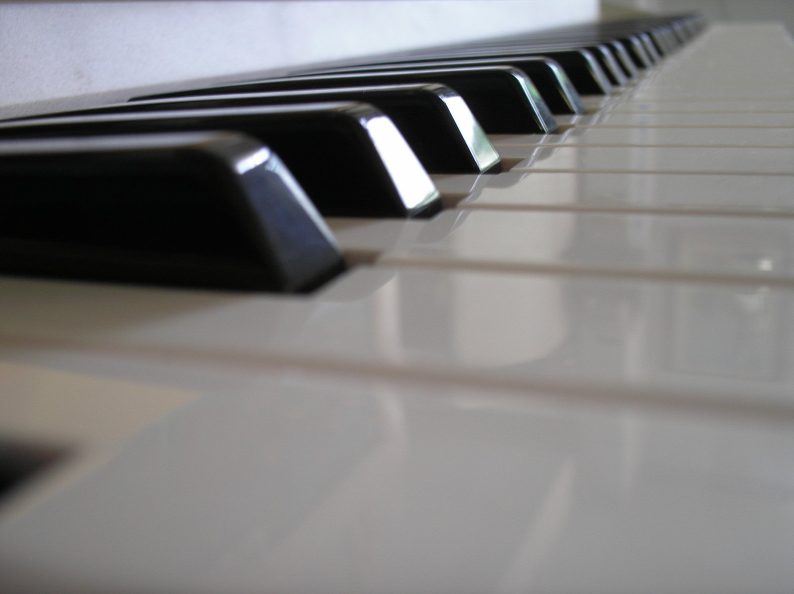 several white and black piano keys and the reflection of each other on top