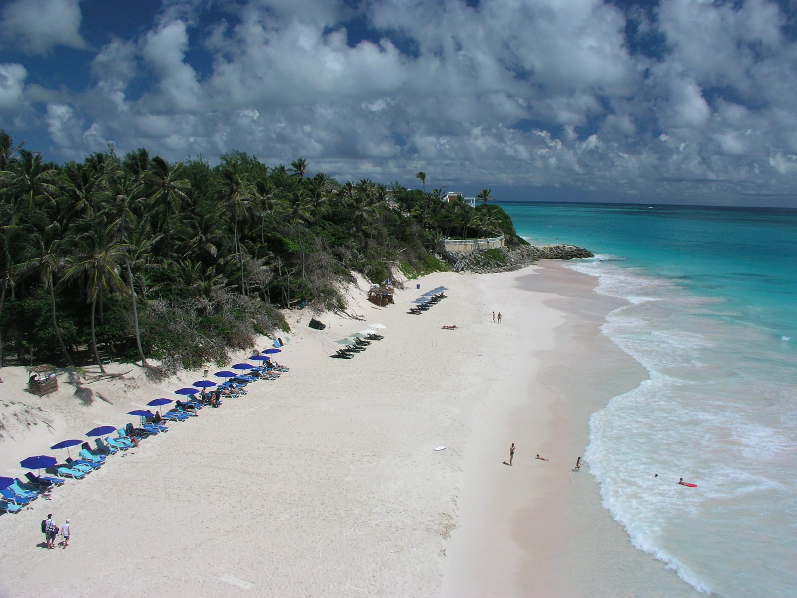 a beautiful white beach filled with blue and green umbrellas