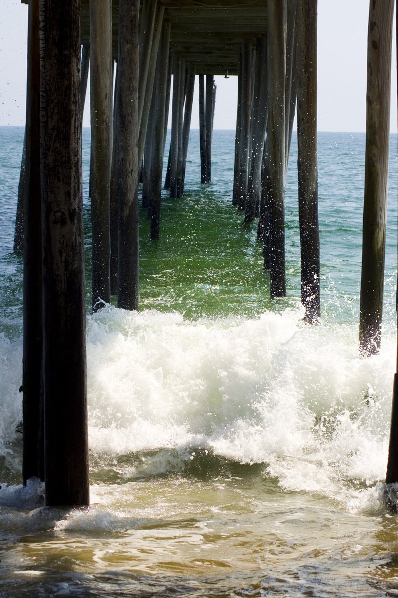 waves are breaking under a pier on the beach