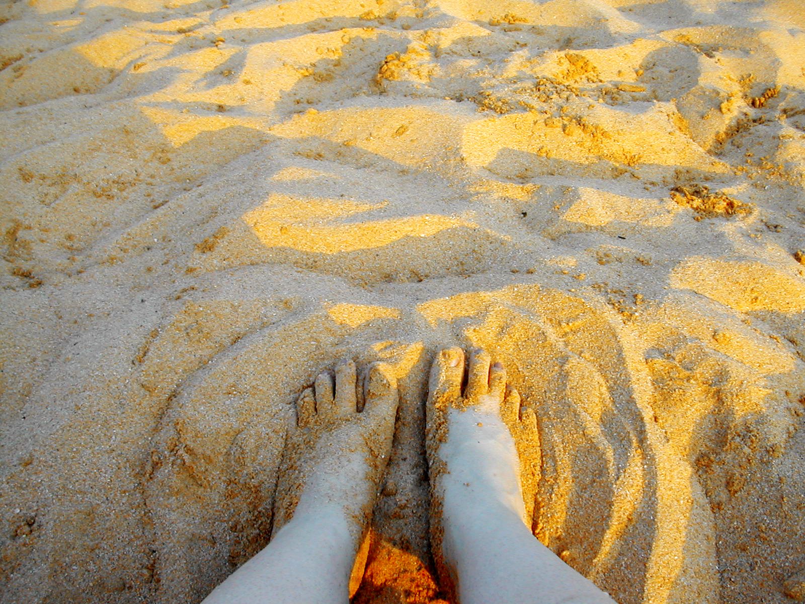 a person has their foot in the sand of the beach