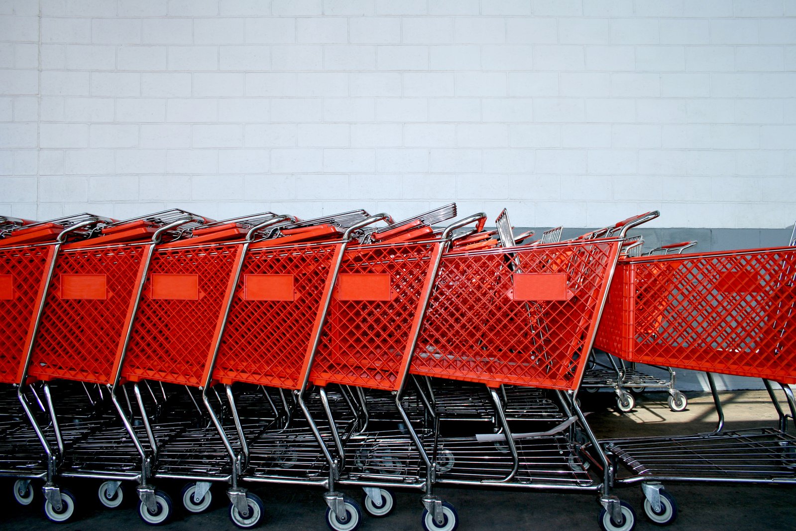 many orange shopping carts are lined up in a row