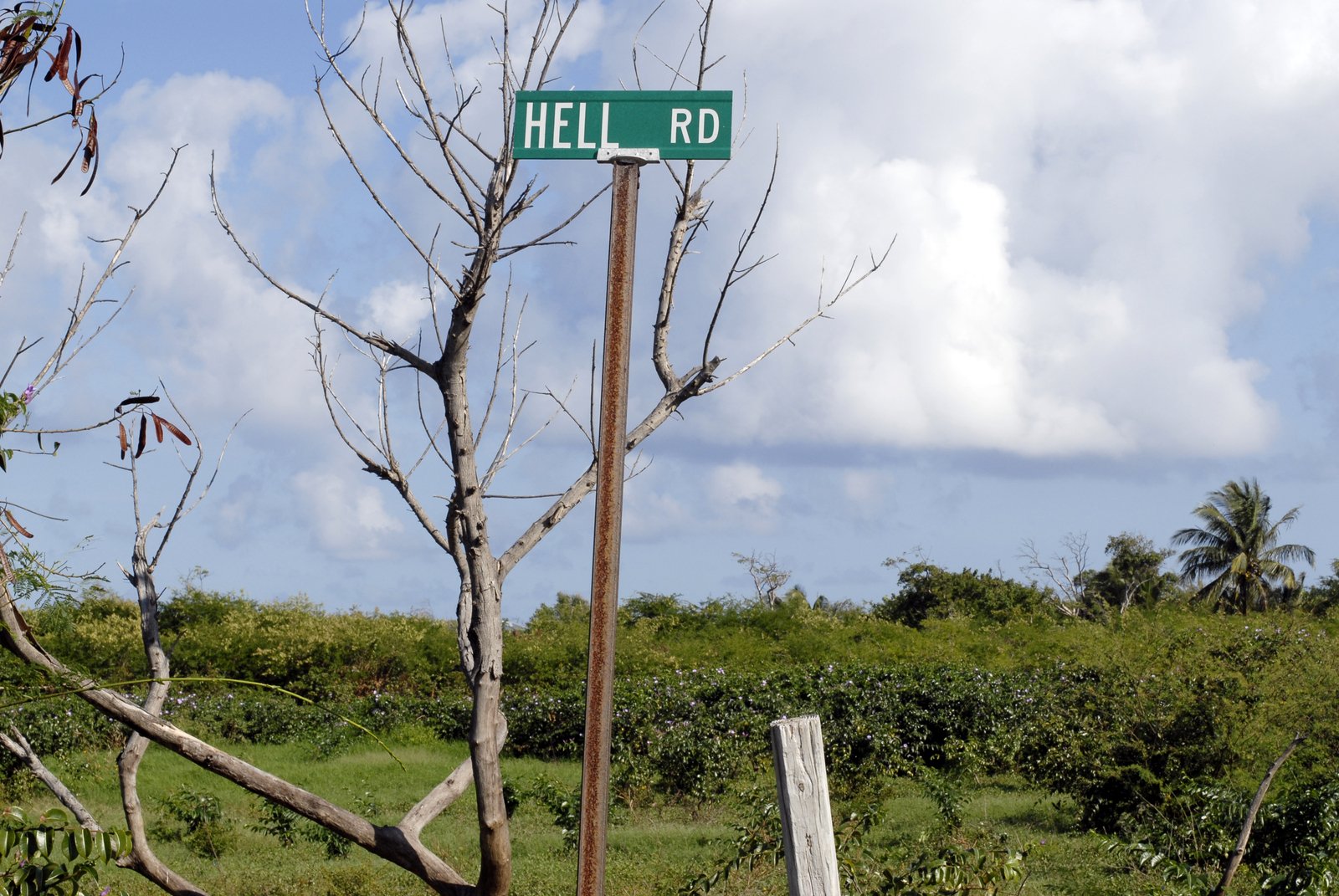 the sign for hell road is hanging on a metal pole