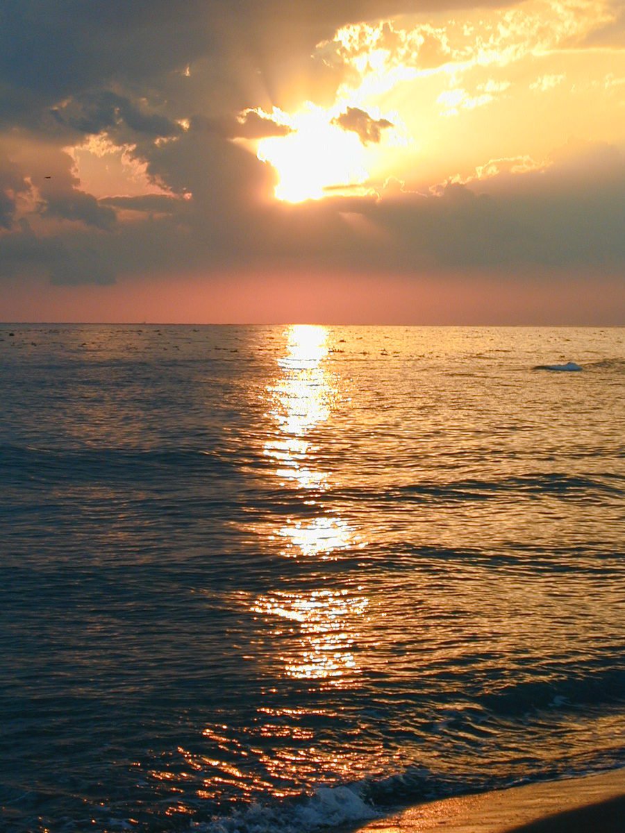 a sunset seen from the beach with calm waters