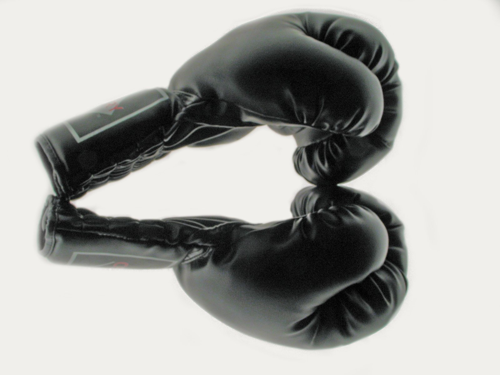 pair of black boxing gloves sitting against white background