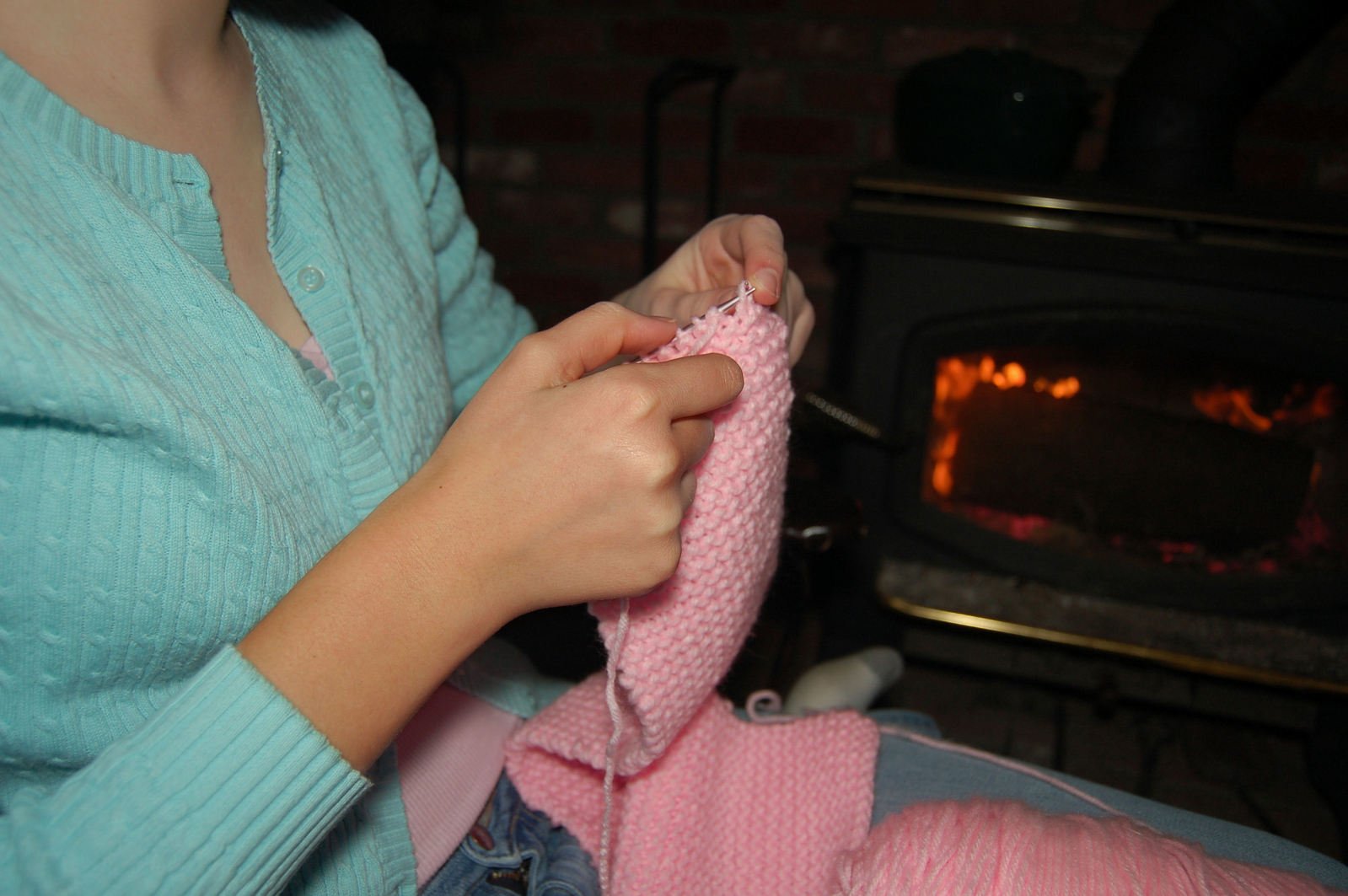 there is a woman knitting clothes in front of the fire