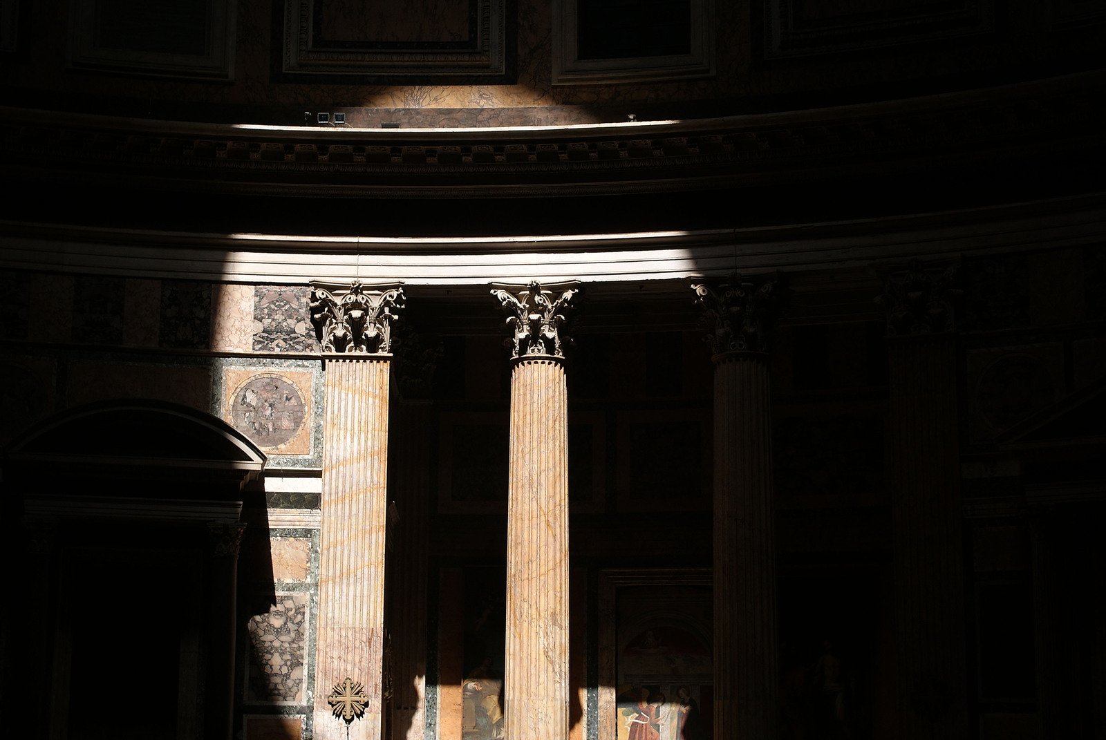 three large pillars in a room with dark walls and flooring