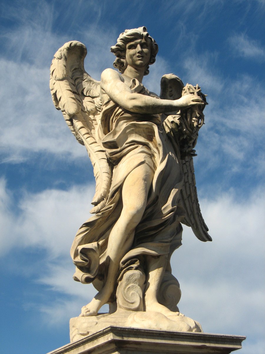 a statue holding an owl with the sky behind