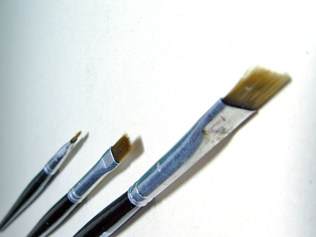 3 brushes and some other different sized pieces of art
