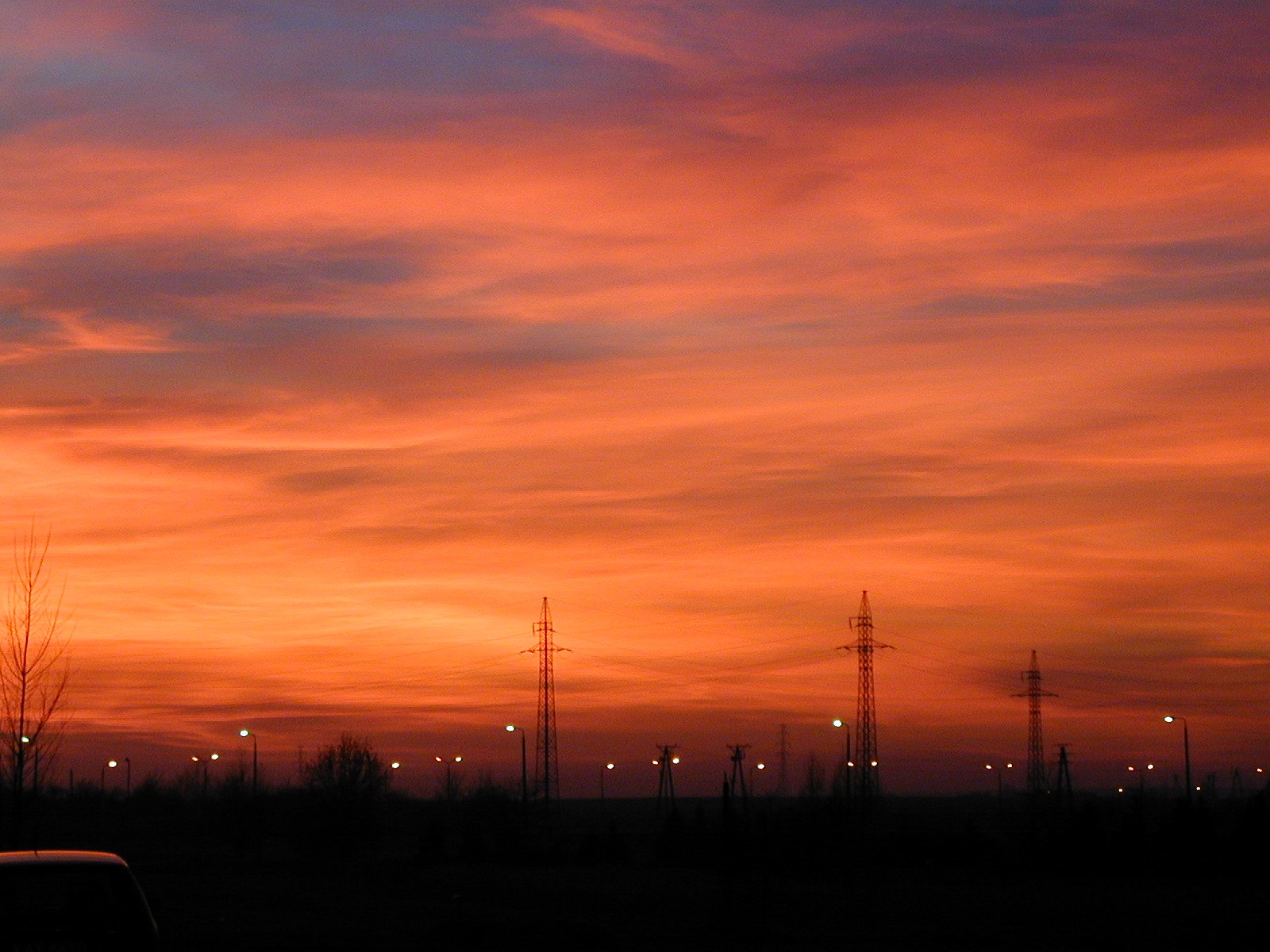 sunset, with telephone towers and cars parked in silhouette