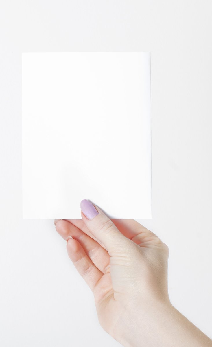 a person's hand holding a sheet of paper over a white surface