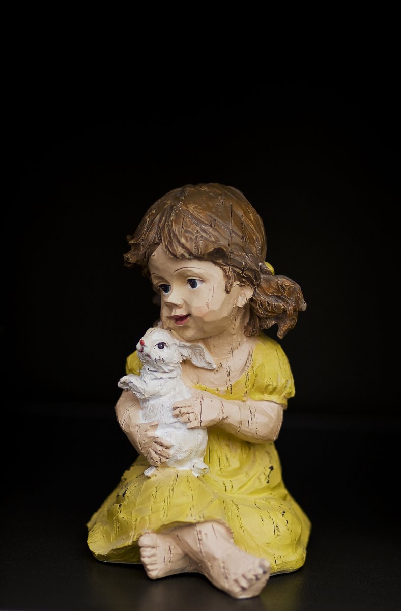a porcelain statue of a girl holding a cat