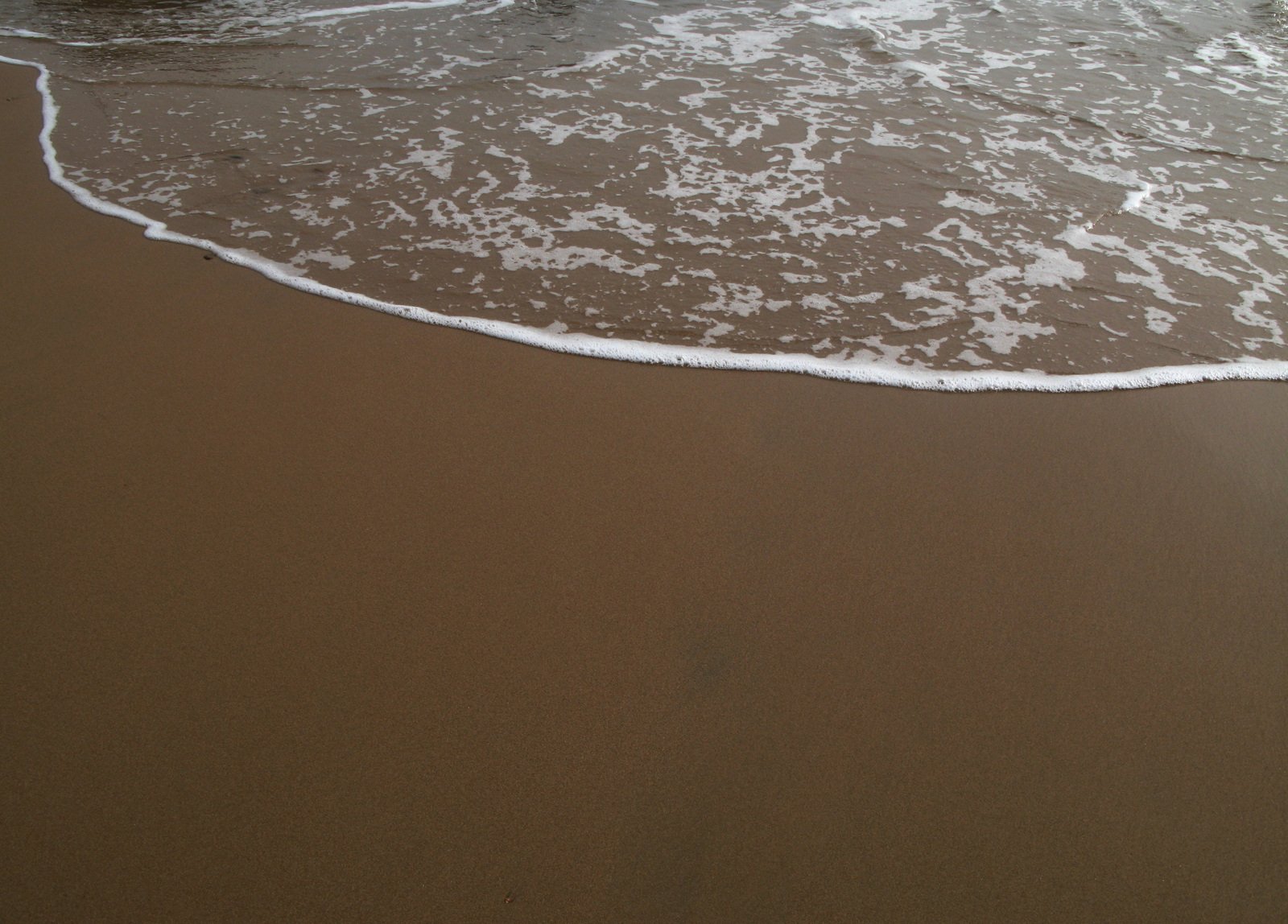 some water waves on a sandy beach by the shore