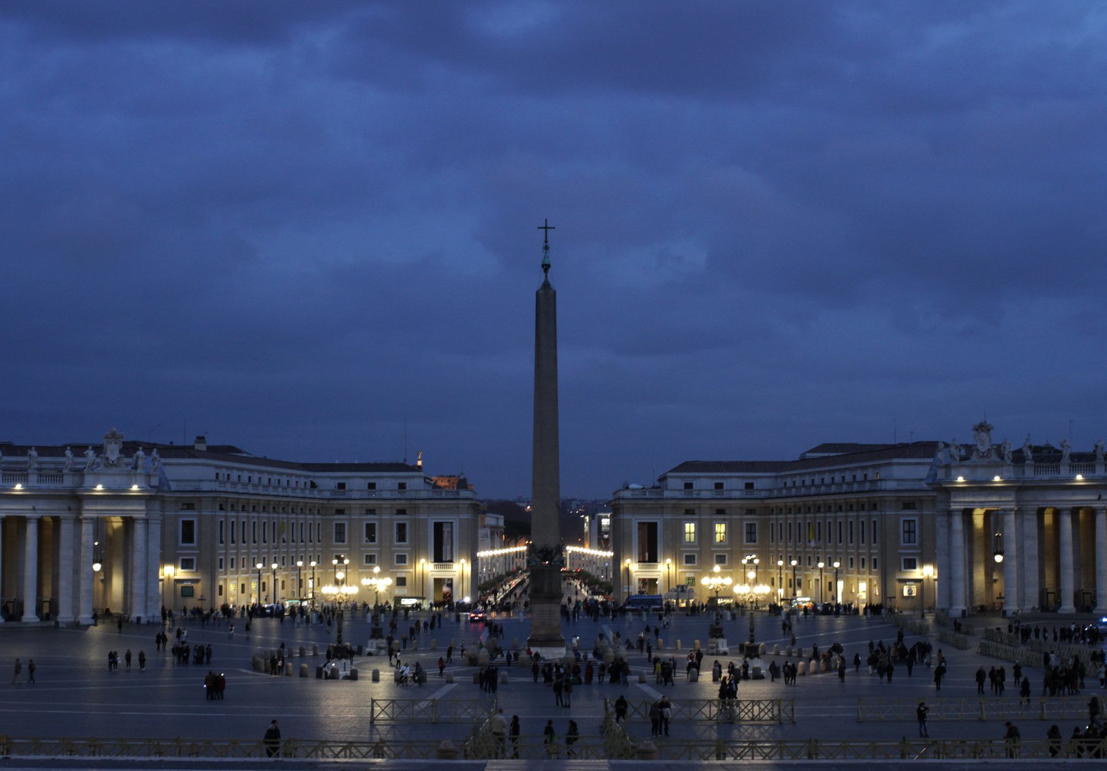 the evening scene of a city square with people walking around