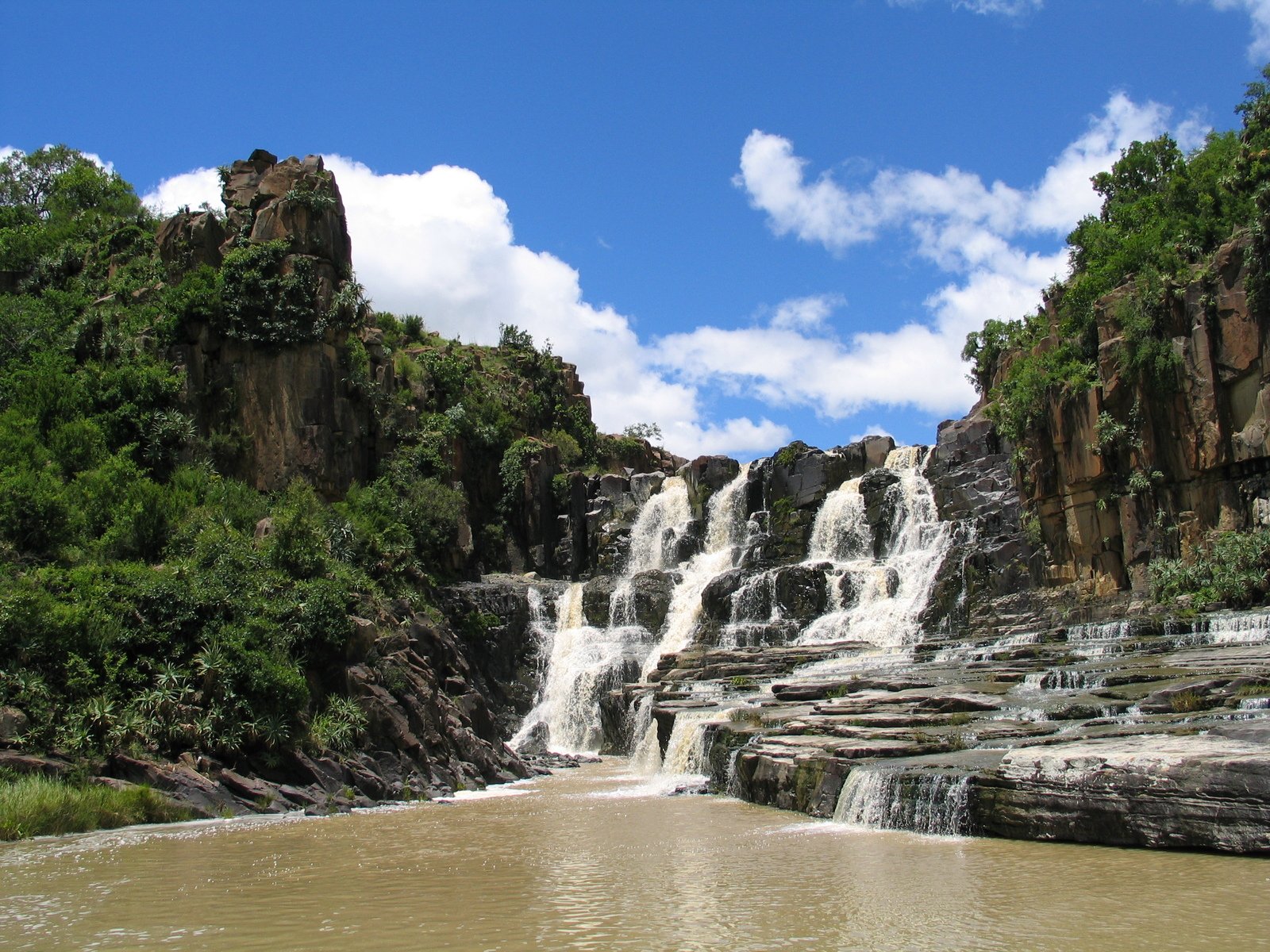 a lake surrounded by some tall rocks next to a waterfall