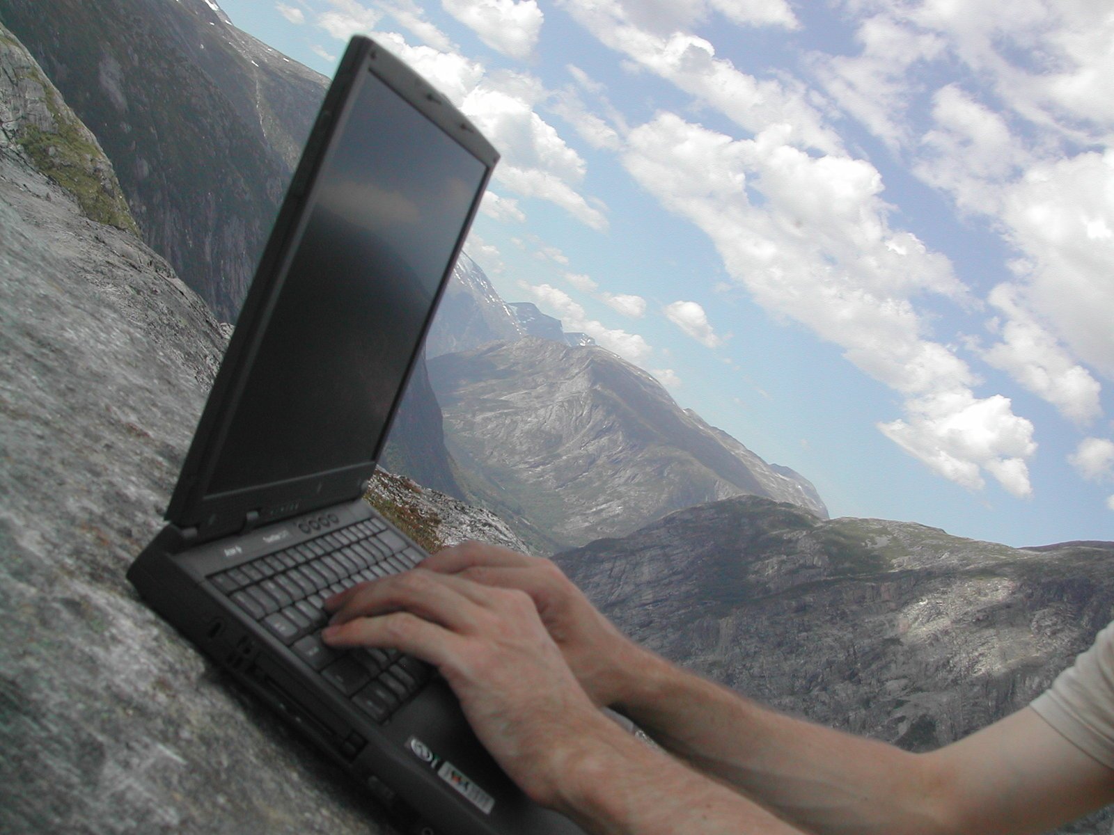 a person is using a laptop computer at the side of a cliff