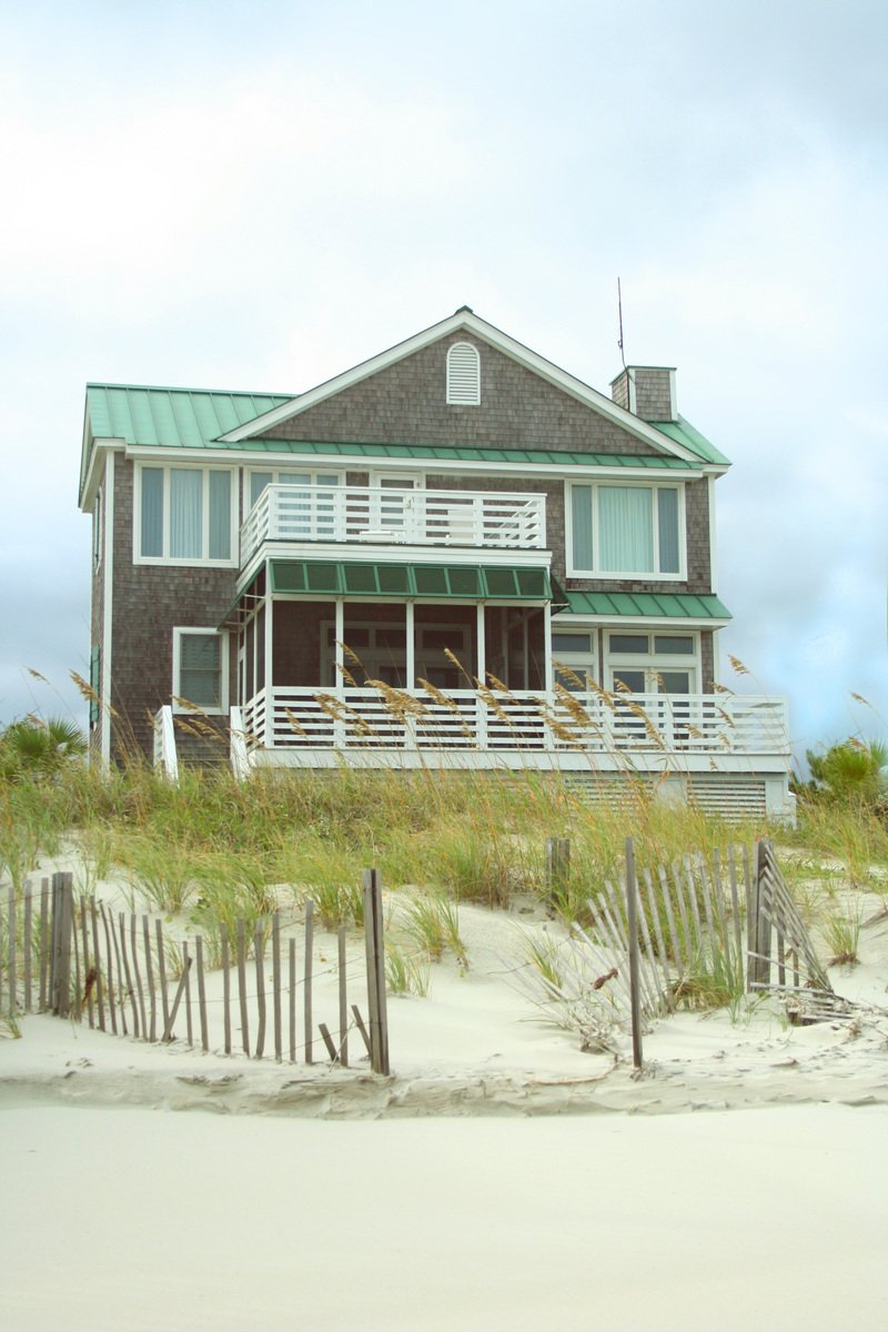 a large beach house on top of sand with a blue roof
