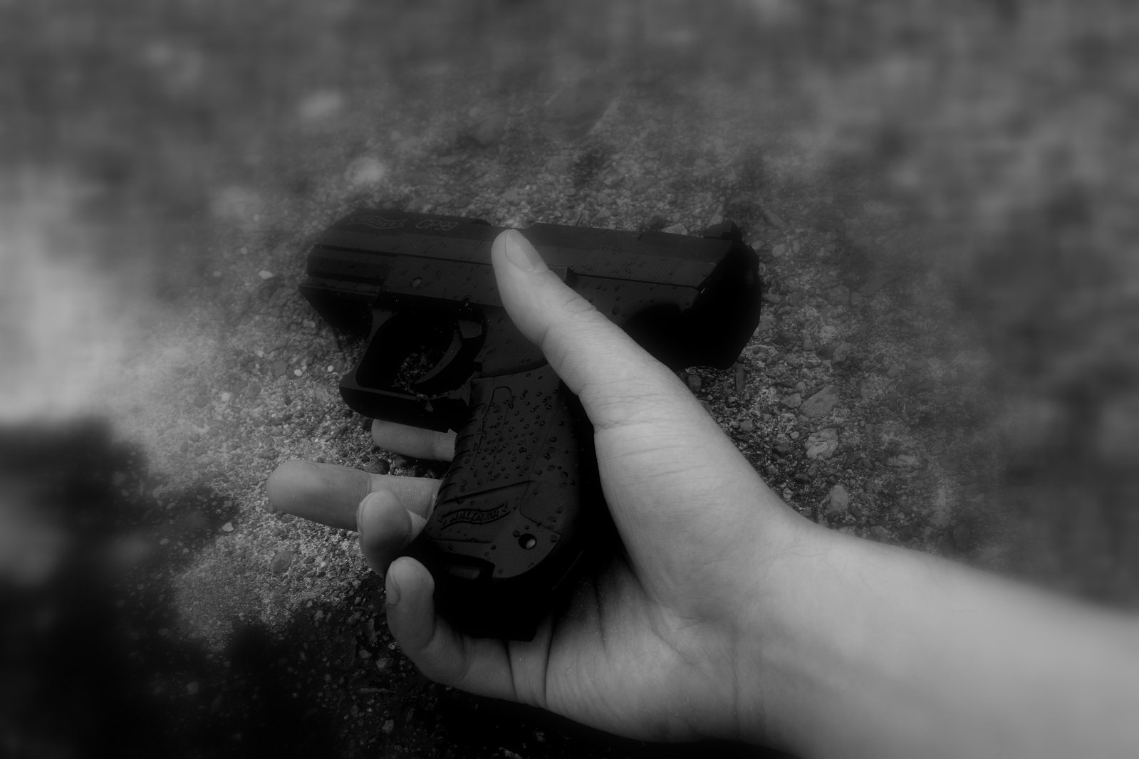 a hand holding a gun on top of concrete