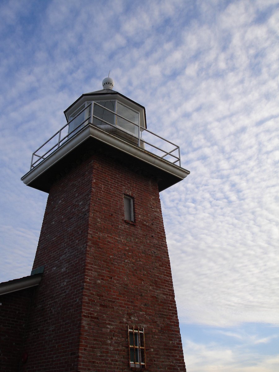 an old lighthouse sits tall in front of the sky