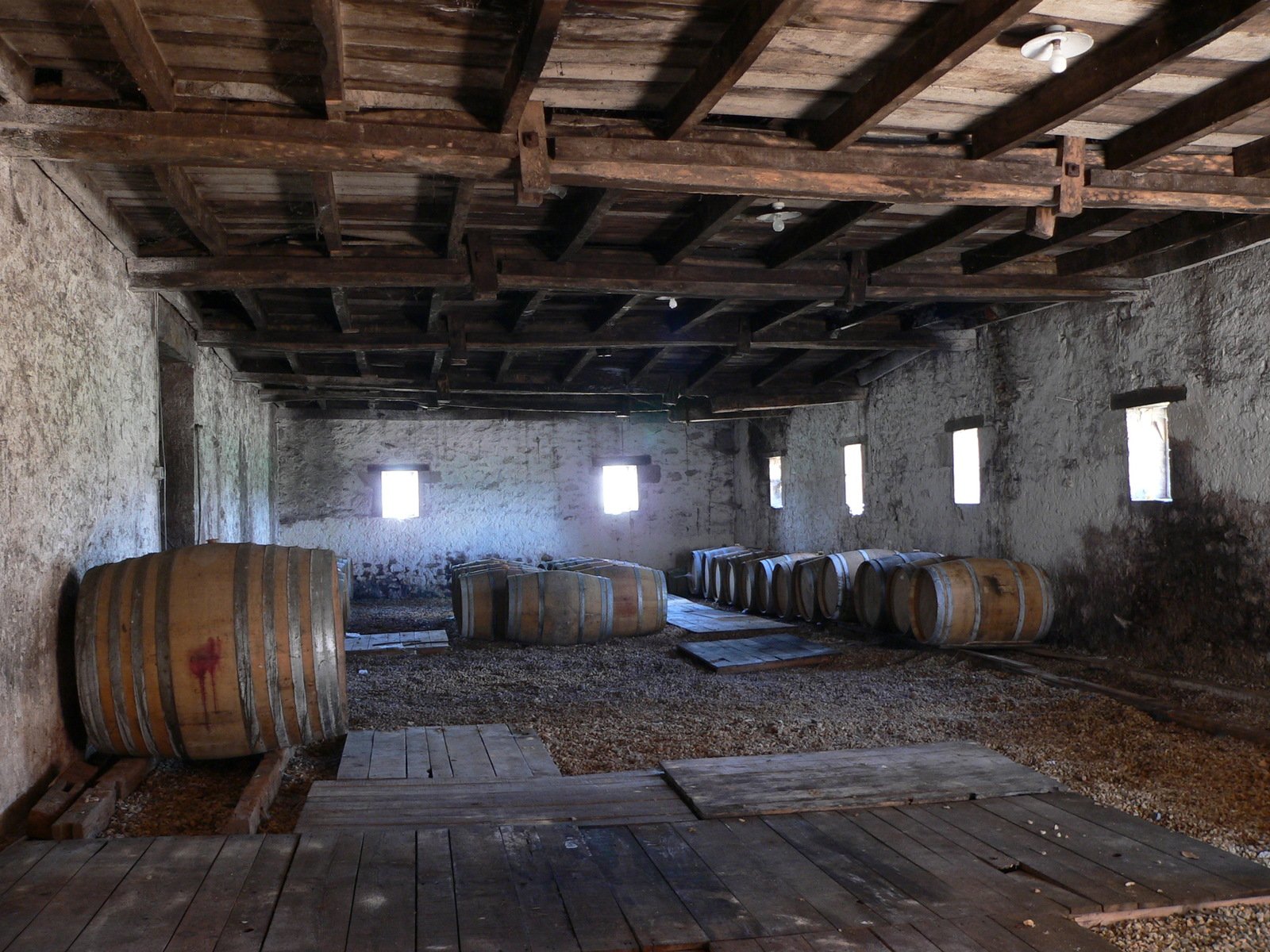 wine barrels in a run down building filled with lots of wood