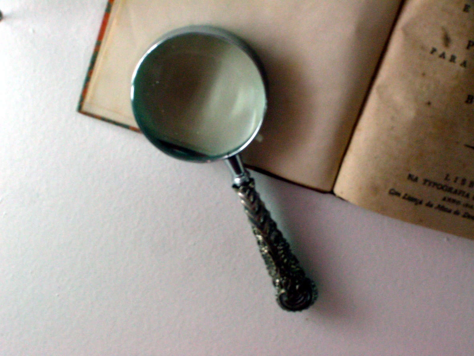 an antique magnifying glass and book are lying on a table