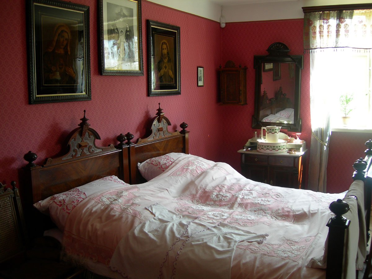 a bed with pink sheets in a red room