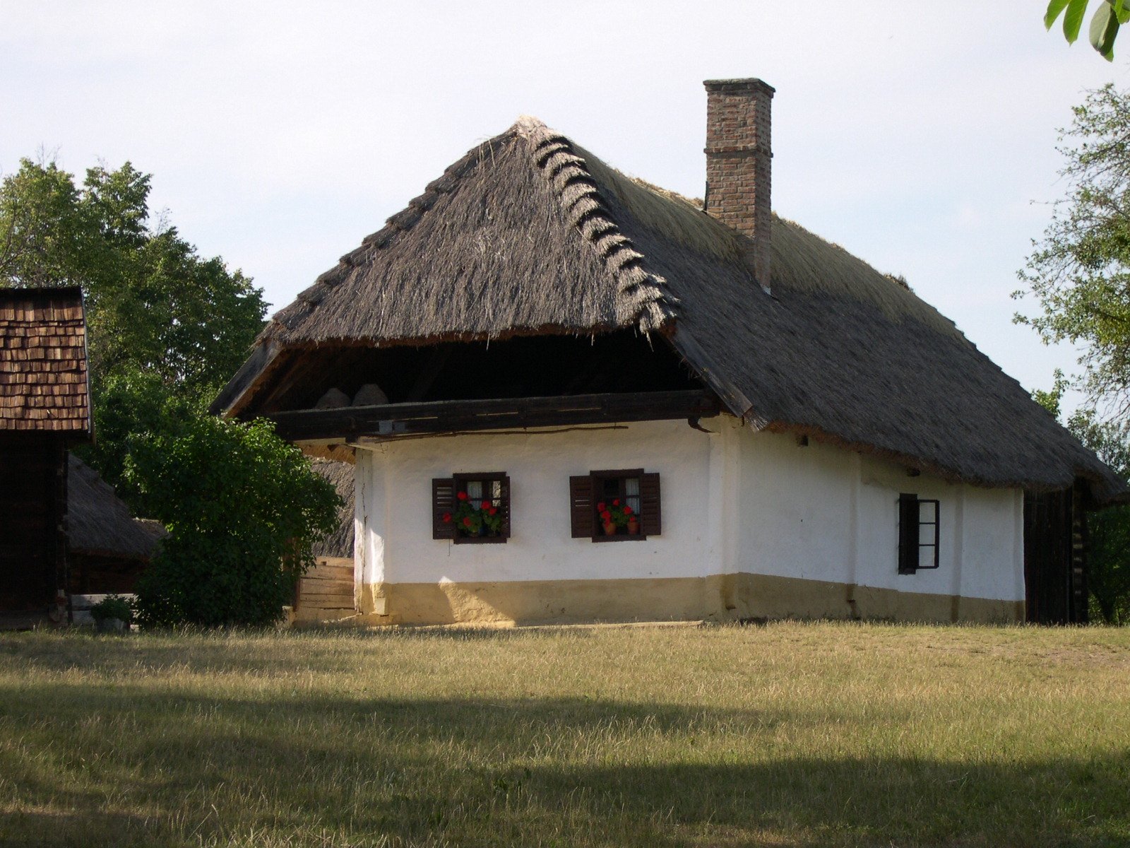 a traditional cottage with thatched roof and two windows