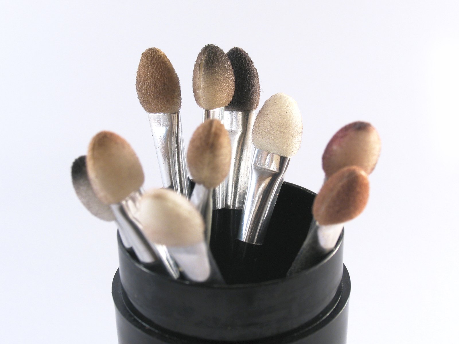 a cup is filled with makeup brushes on a white background