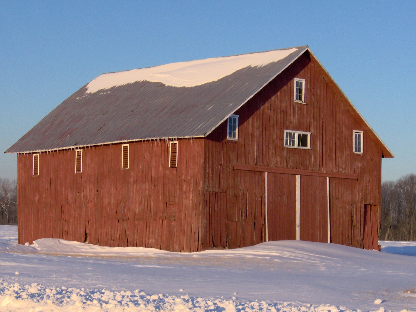 an old barn with snow on the ground