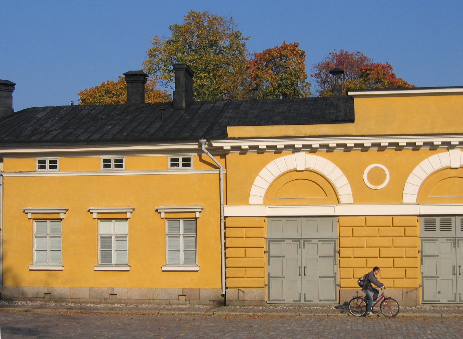 a person riding a bicycle by the side of a building