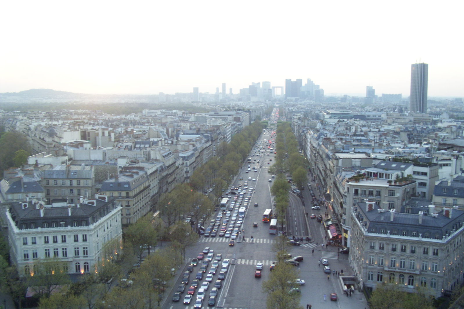 a street with cars lined up on both sides of it and lots of tall buildings