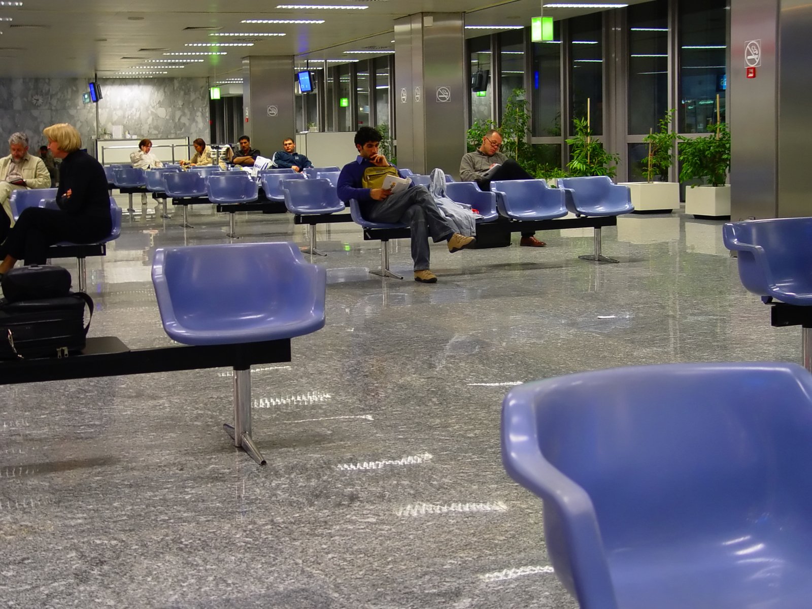 the airport has many blue chairs for waiting people