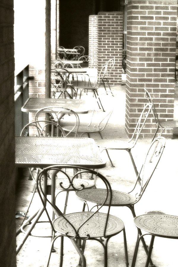 black and white pograph of tables and chairs lined up on a porch
