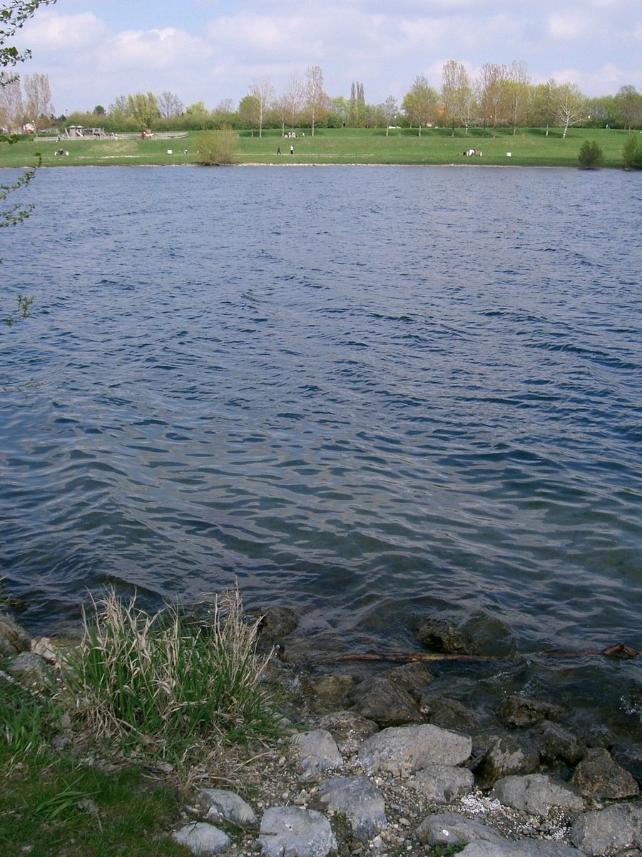 an empty lake surrounded by green grass, rocks and grass