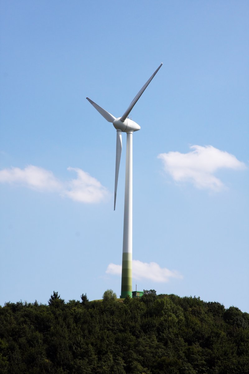 a wind turbine stands high over the green hills