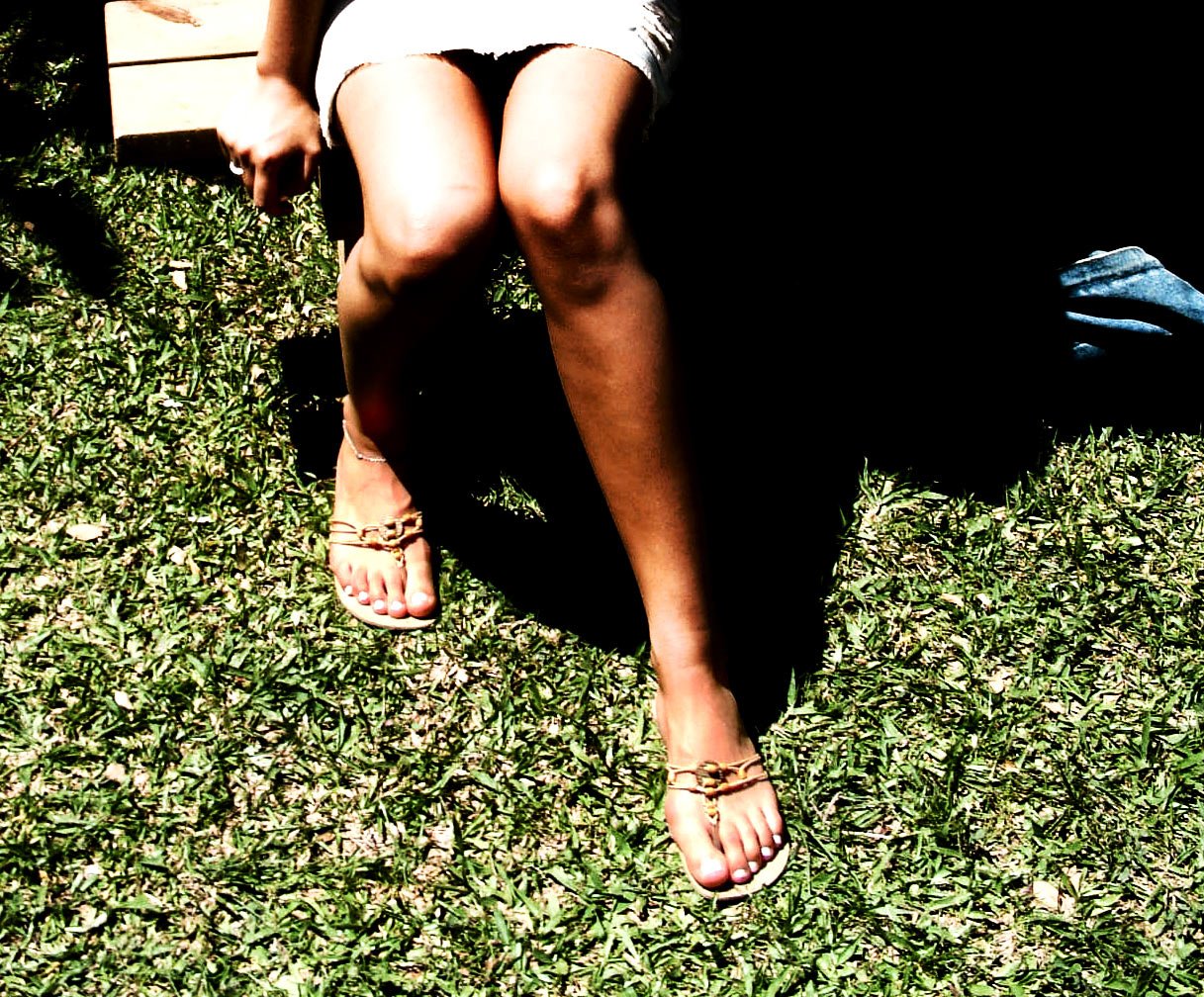 two women sitting on a bench in a grass covered area