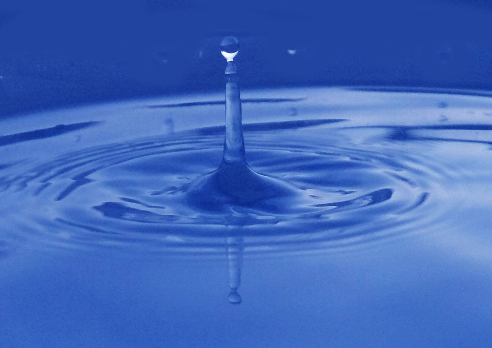 a blue droplet is reflected on the surface of the water