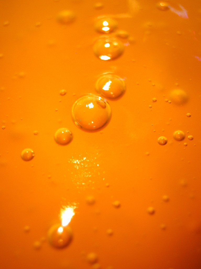 three bubbles are floating on an orange liquid