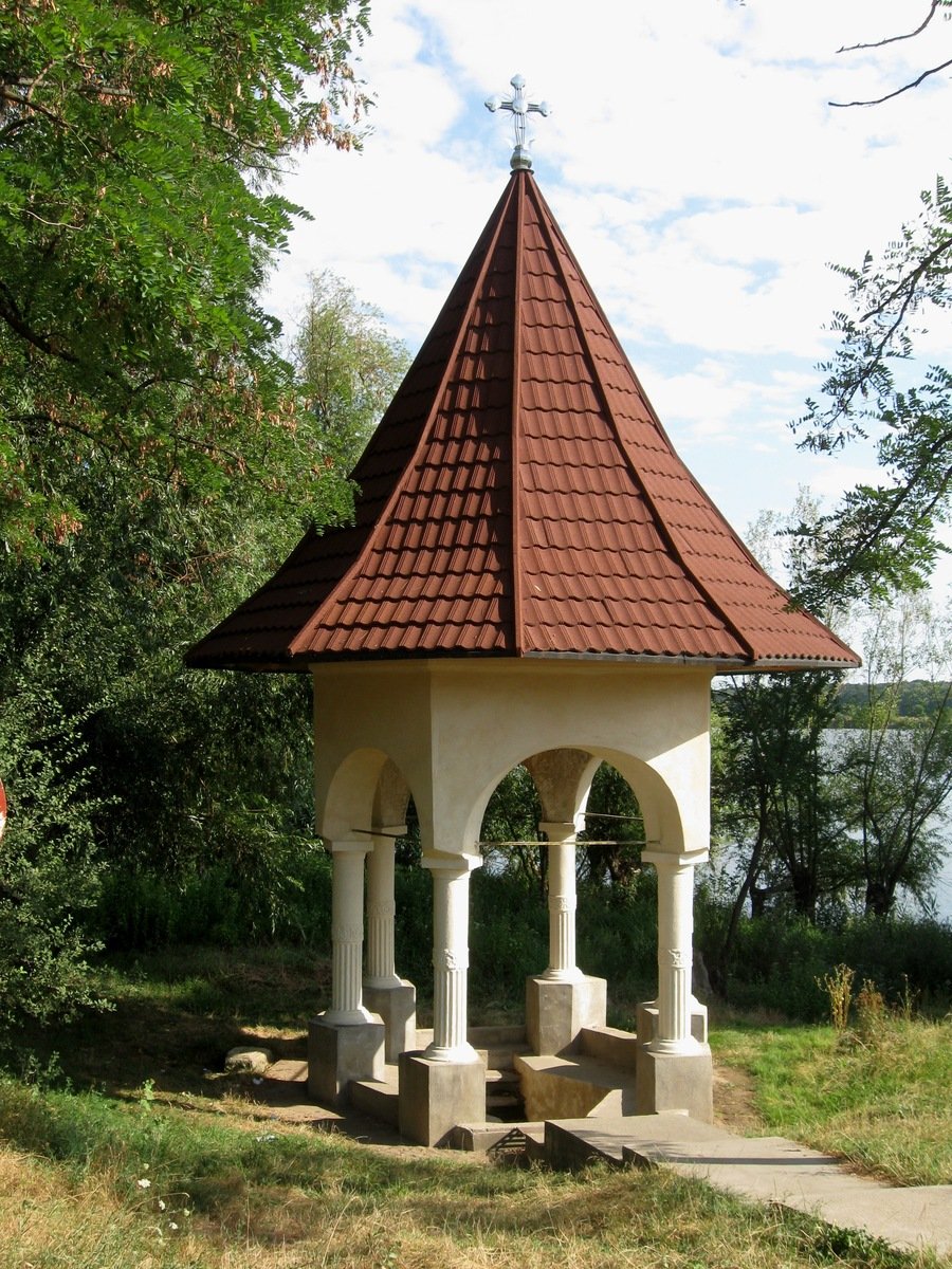 a clock on top of a white tower by water