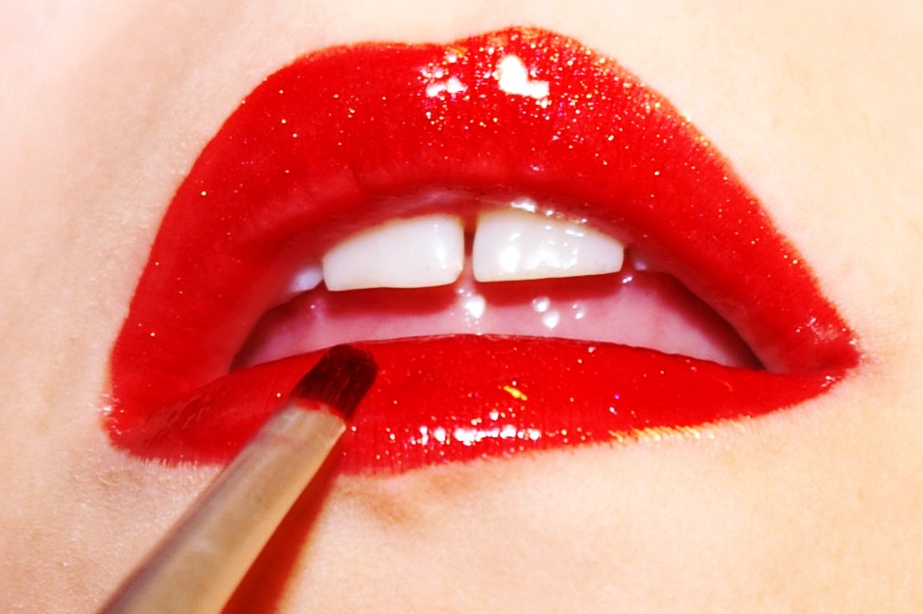 a lady putting glitter on the lip and a lipstick brush