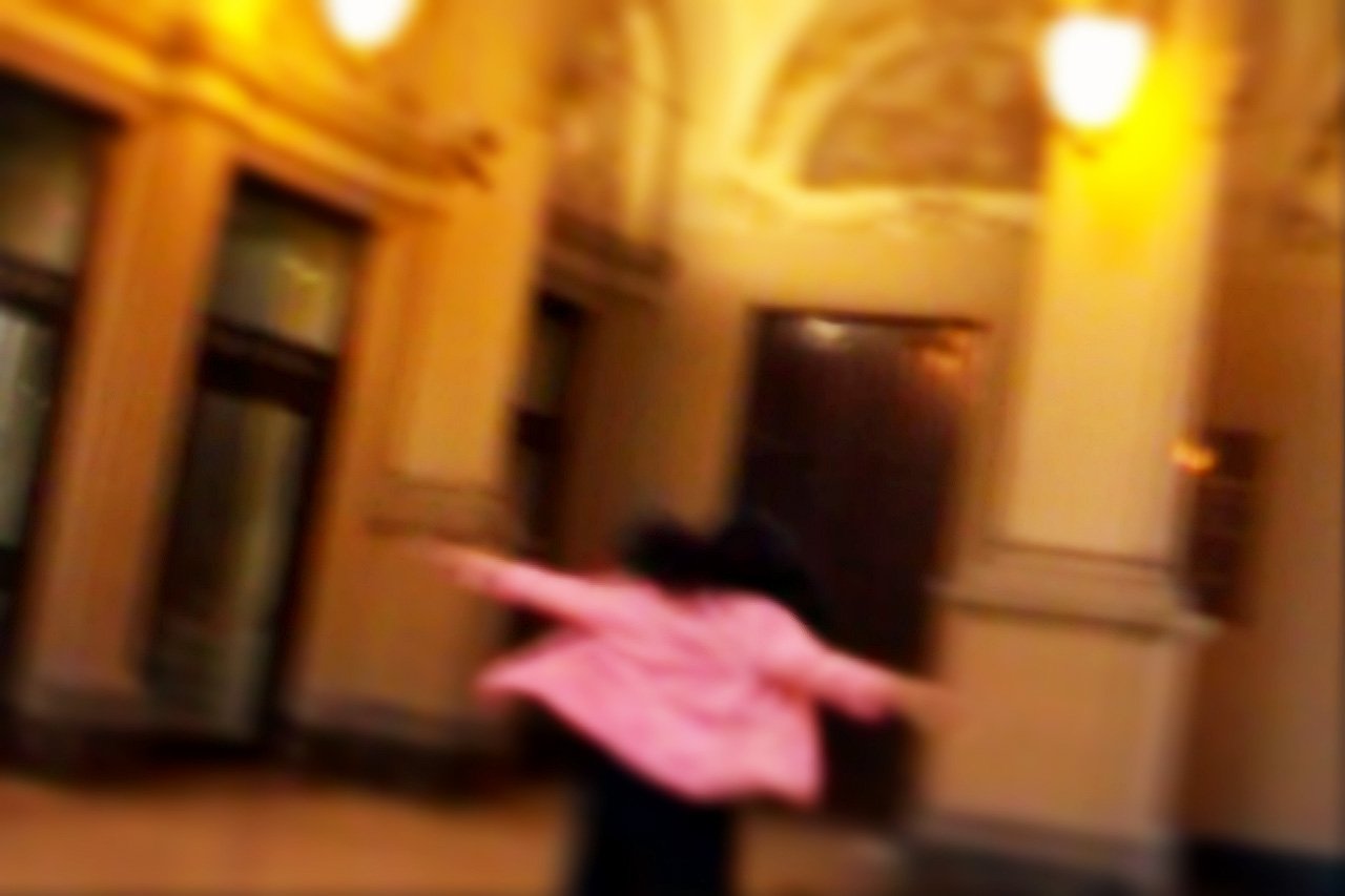 blurred po of a person holding a piece of luggage in an old building