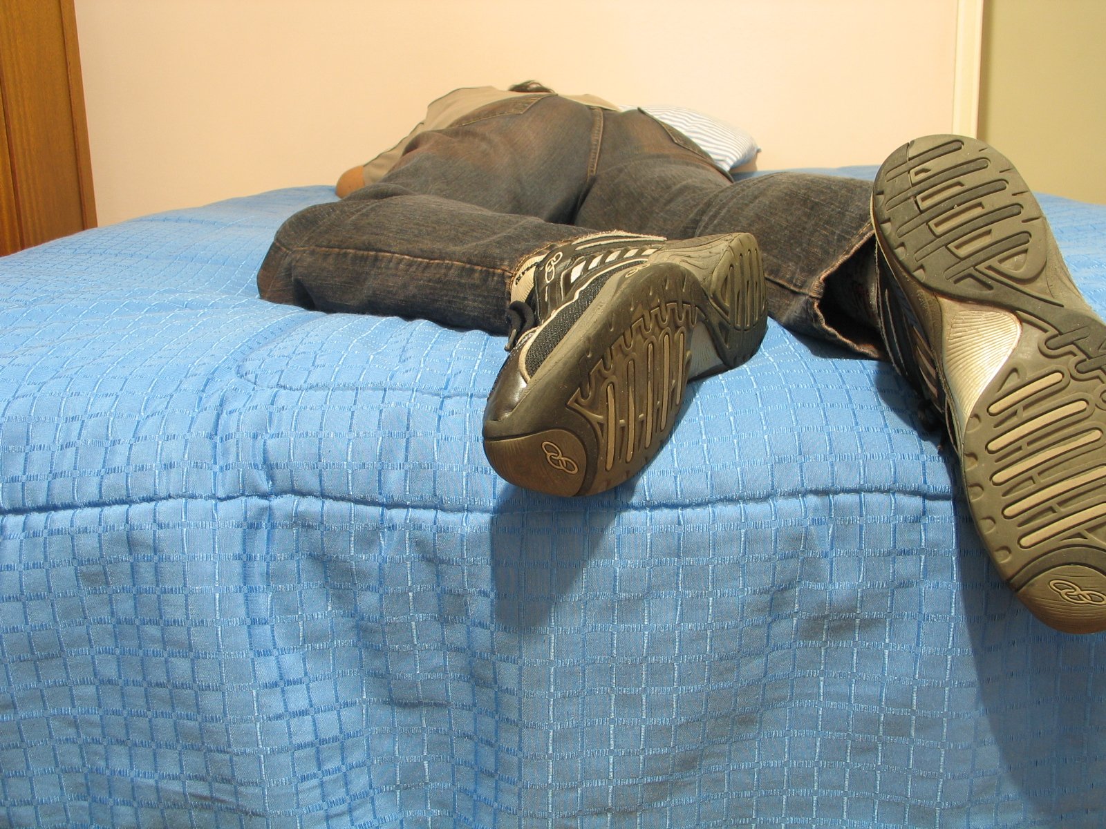 two pairs of feet resting on top of the bed