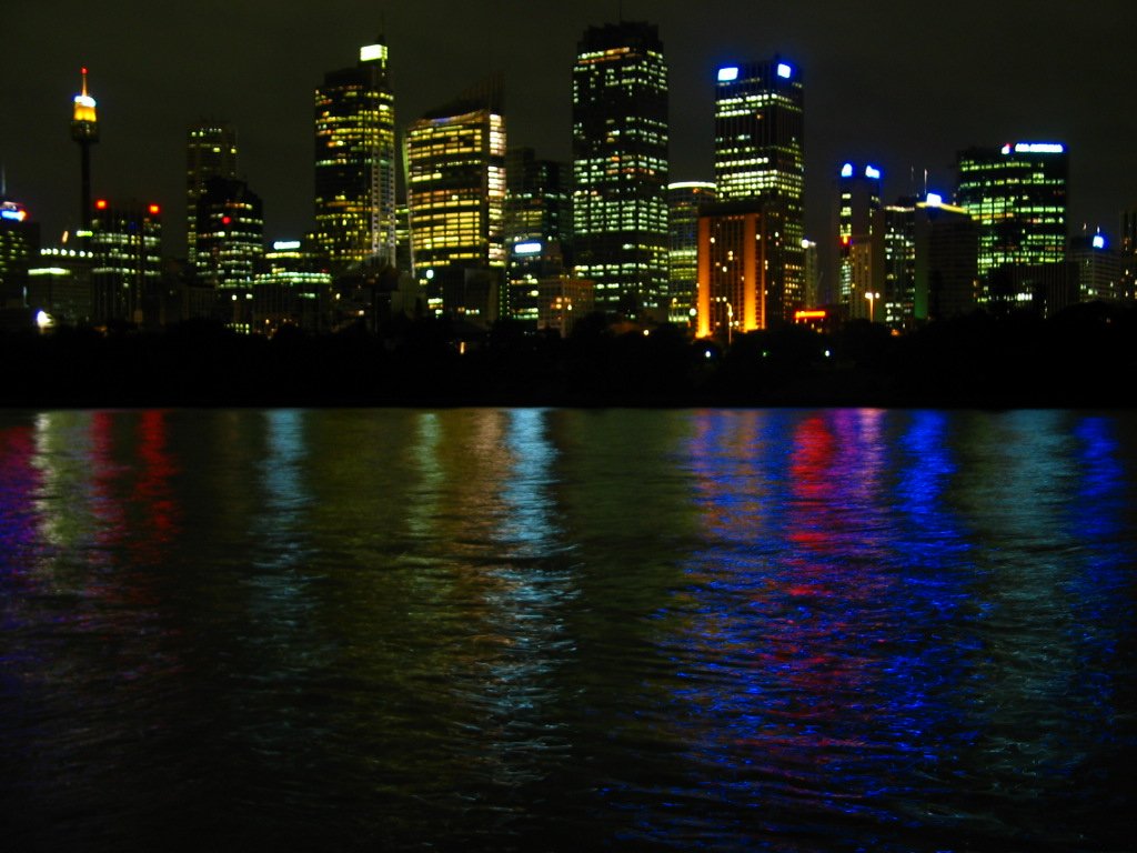 a city skyline lit up in blue, green, and red lights