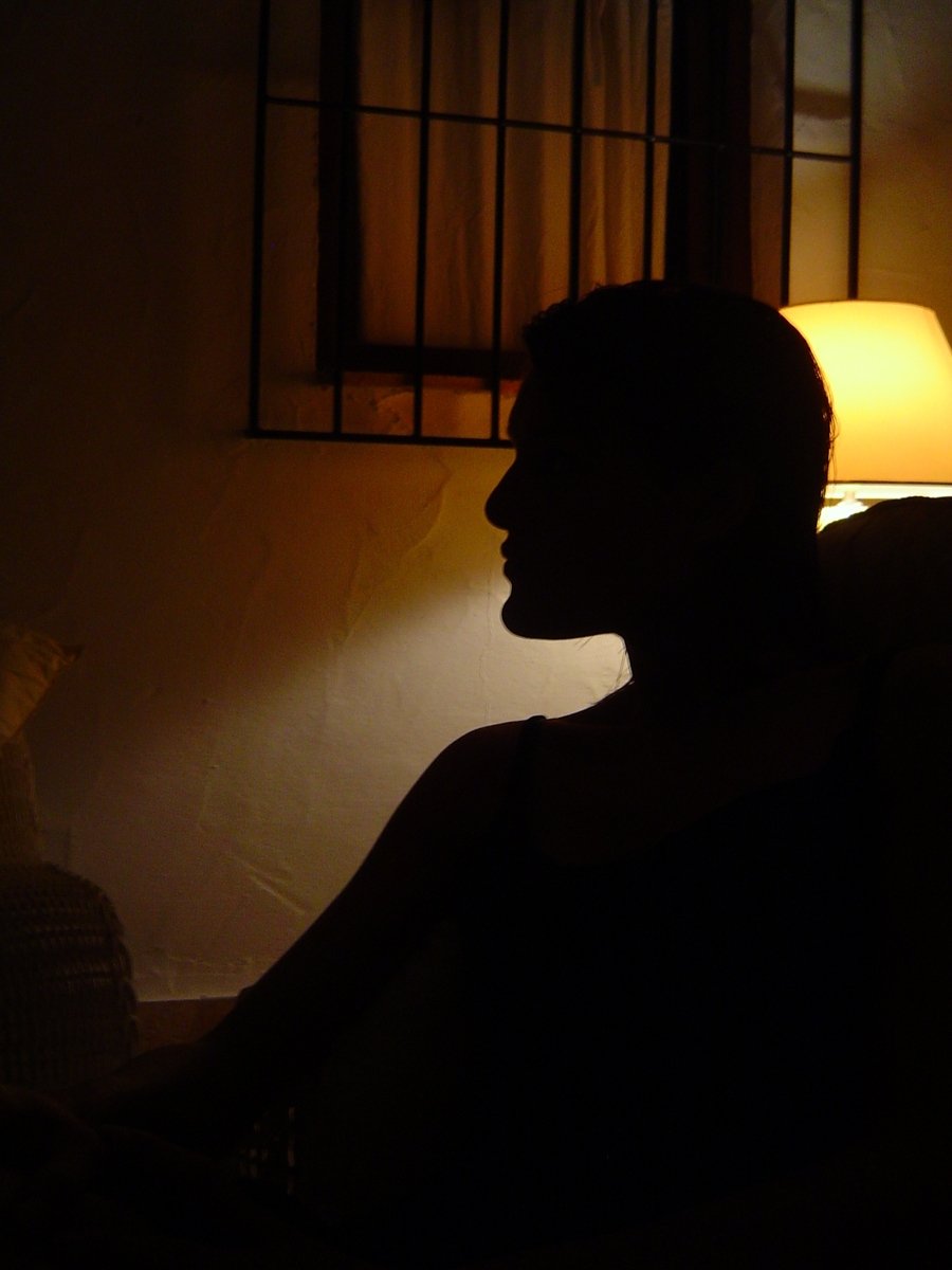 man sitting in the dark under a lamp