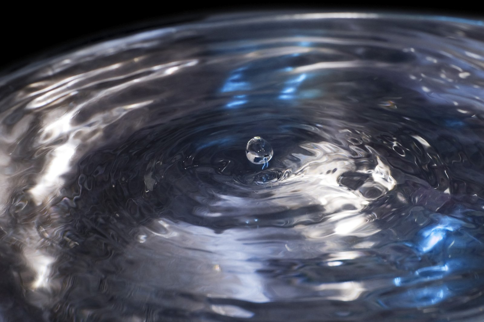 the top half of a glass bottle with water droplets